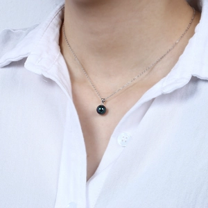 Minimalist silver chain necklace with a peacock green round pearl pendant on a model