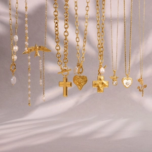 Detalle de collares dorados con perlas y colgantes diversos sobre fondo de satén