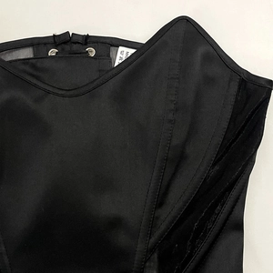 Detail of satin and mesh stitching with metal eyelets on a black corset top