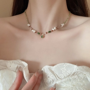 Detail of 18k gold plated pearl necklace with green stone on model with lace dress