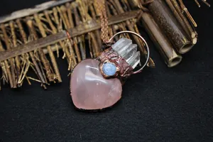 Detail of rose quartz heart pendant with raw copper wrap and white crystal clusters