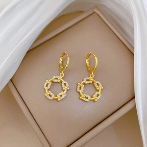 Detailed macro view of gold-plated chain link earrings with shimmering crystals on silk