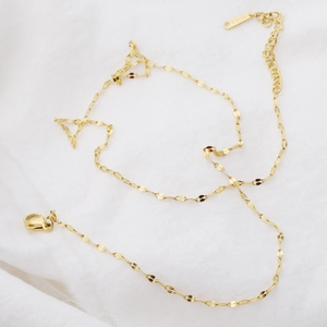 Golden stainless steel lip chain necklace with adjustable lobster clasp on white fabric