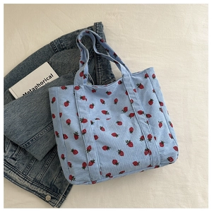 Gedetailleerde close-up van lichtblauwe corduroy tote bag met aardbeienprint en zakje