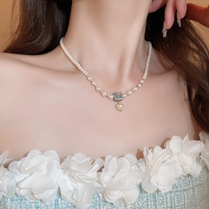 Close-up of French style pearl necklace with blue gemstone pendant on woman neck
