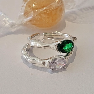 Macro view of irregular silver zircon ring with green oval gemstone and lava texture