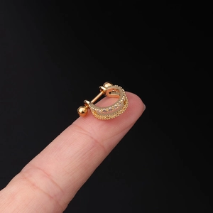Macro shot of 20G gold-plated curved cartilage stud with zircon inlay and screw ball back