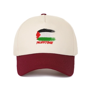 Dettaglio del ricamo della bandiera palestinese e testo su cappello bicolore