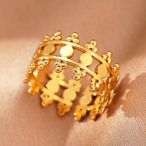 Macro shot of gold hollow crown ring with geometric circles on champagne satin silk