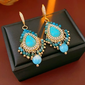 Gros plan détaillé de boucles d'oreilles bohèmes avec pierres turquoise et glands dorés