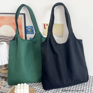 Detail view of large dark green and black canvas tote bags with thick shoulder straps