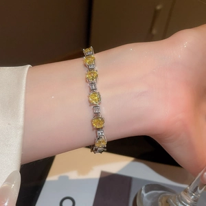 Detailed shot of sparkling yellow zircon and square diamonds on a silver charm bracelet