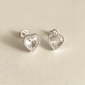 Detailed close-up of heart-shaped zircon earrings with elegant silver milgrain edge design