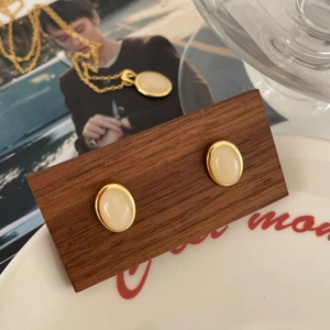 Détail de boucles d'oreilles ovales dorées vintage et collier avec pierre crème