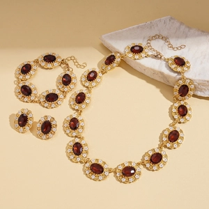 Vintage gold jewelry set with red oval gemstones and white floral enamel accents