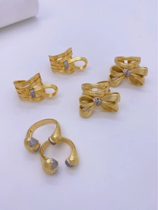 Detailed view of six 18K gold-plated bow rings with brushed finish and inlaid crystals