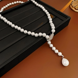 Detail of Y-shaped necklace featuring zircon leaf clasp and large teardrop pearl pendant