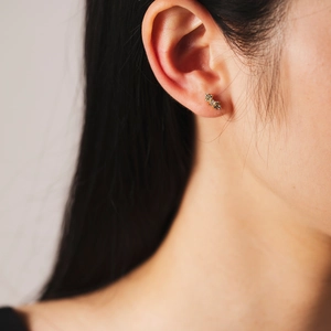 Elegant gold leaf-shaped stud earrings with three sparkling diamonds worn by a model
