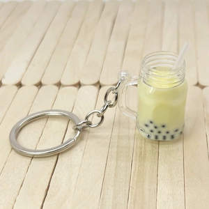 Macro view of a miniature bubble tea keychain with yellow fluid and black pearls