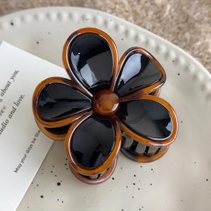 Detailed view of an acrylic five-petal flower hair claw clip with black petals and brown trim