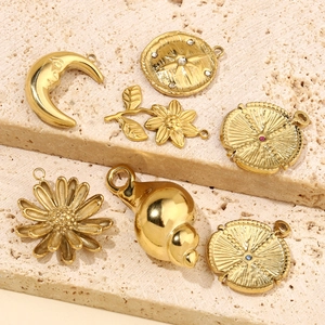 Gold plated stainless steel moon and star pendants set with colorful stones on stone surface
