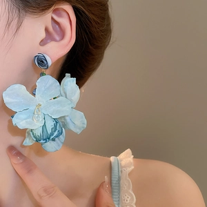 Detail of blue fabric flower earrings with a hanging water drop pendant on a model