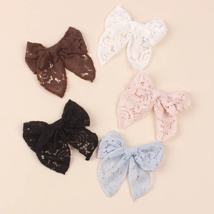 Detailed flat lay of five lace bow hair clips in brown, white, pink, black, and blue colors