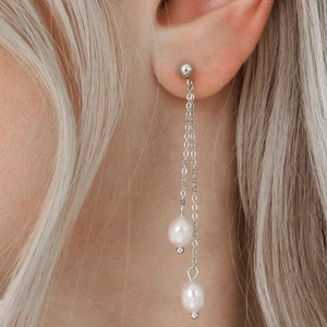 Detailed view of silver long tassel earrings with pearls on a model for a luxury look