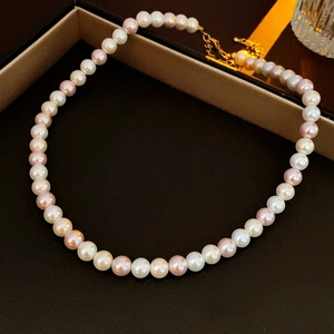 Detailed macro view of multi-color freshwater pearls with golden metallic clasp and chain