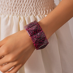 Detail showing high-gloss leopard print acrylic resin cuff bracelet on woman's wrist