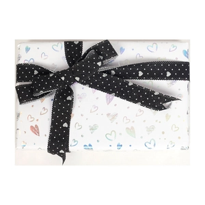 White gift wrapping paper with holographic hearts and black polka dot ribbon bow