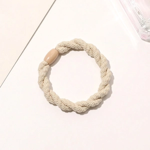 Detail of a beige elastic hair tie featuring a knotted texture and plastic fastener