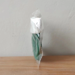 Close-up of a green knitted Christmas stocking ornament in a transparent plastic bag
