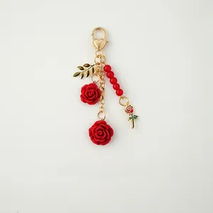 Detail of red resin rose keychain with gold alloy heart clasp and beaded accents