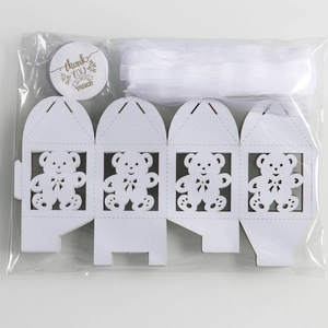 Detail of white hollow bear candy boxes with sheer ribbon and thank you stickers