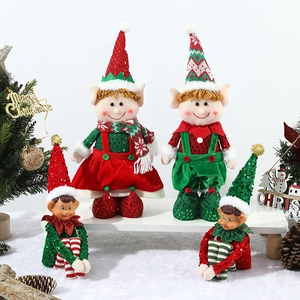 Charming red and green Christmas elf dolls standing on artificial snow with decor