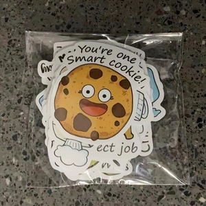 Flat lay of colorful cartoon motivational stickers in a clear plastic bag on a stone surface