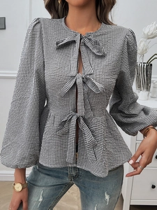Detail of checkered peplum top with bubble sleeves and three front ribbon bows for women