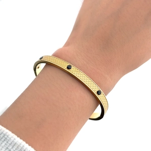 Detailed view of golden stainless steel bracelet with snake scale texture and black stones