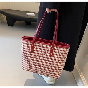 Detail of red houndstooth tote bag featuring elegant textures and gold rivet accents