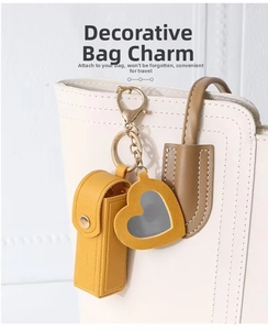 Yellow leather lipstick pouch and heart mirror charm on a white textured handbag