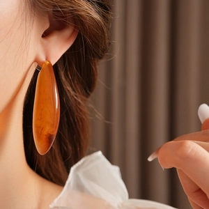 Gros plan d'une grande boucle d'oreille en résine ambre portée par un mannequin