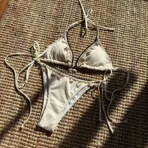 Detailed view of cream textured bikini set with contrast trim and shell charms