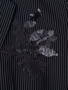 Détail de la broderie de paillettes noires sur le tissu rayé de la veste blazer