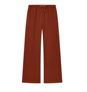 Detail of dark orange wide-leg sweatpants featuring elastic drawstring waistband