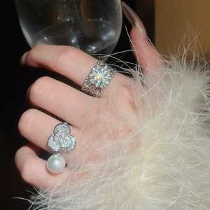Détail de bagues argentées avec breloques fleurs de camélia, perles et cristaux brillants