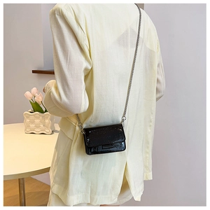 Detailed look at a black crocodile pattern mini square bag with silver chain strap on model