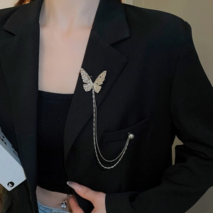 Detailed view of butterfly brooch with silver chain and pearl on a black suit jacket