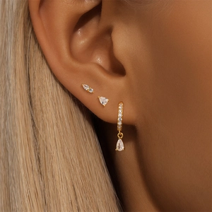 Detail shot of gold earring set featuring teardrop and marquise zircon stones on ear