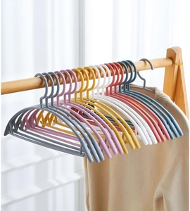 Group of multi-colored non-slip plastic hangers hanging on a wooden closet rod